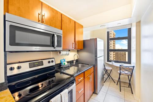 a kitchen with a stove and a microwave at Diamond Head Views Retreat with Free Parking & Near Waikiki Beach! in Honolulu