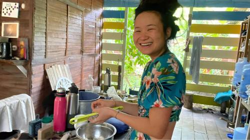 a woman standing in a kitchen preparing food at Hostel AYA-NI in Pucallpa