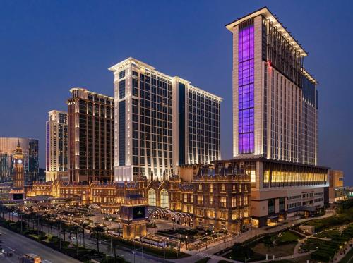 a tall building with purple lights on it in a city at Sheraton Grand Macao in Macau
