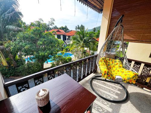 a porch with a swing and a table on a balcony at Amy Village Apartments & Digital Hub in Lamai