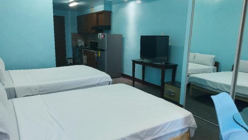 Una pequeña habitación con dos camas y un televisor. en MANILA BAY FRONT DELUX Pearl of the orient, en Manila