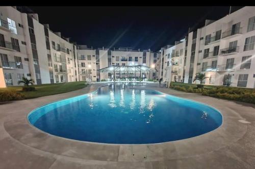 - une grande piscine en face d'un bâtiment la nuit dans l'établissement Hermoso departamento en Acapulco, à Acapulco