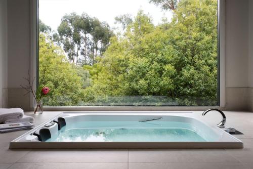 a bathroom with a bath tub in front of a window at Schafhalle in Hepburn Springs