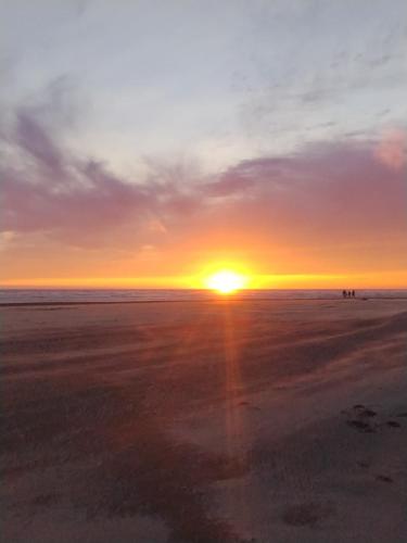 a sunset on the beach with people in the distance at Lighthouse Suites Inn in Ocean Shores