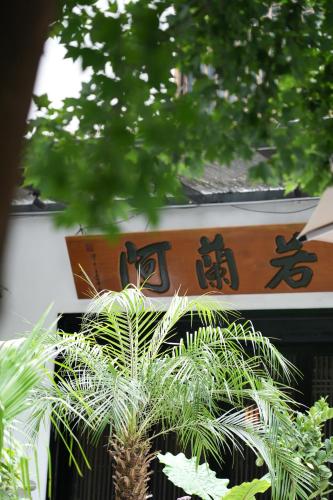 a sign with asian writing behind a palm tree at Tingjian Lingyin Alanruo Design Homestay in Hangzhou