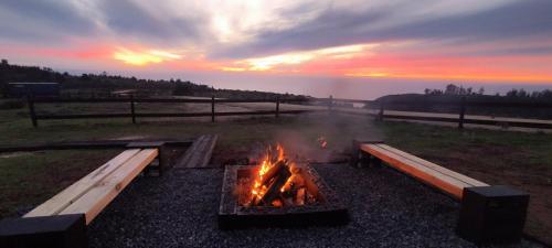 a fire pit in a field with a sunset in the background at Casa Black hostal puertecillo - matanzas in Polcura
