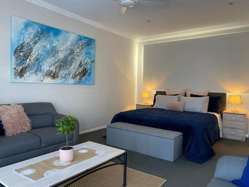 a bedroom with a bed and a couch at Mountain Views (3 min drive to beach) in Gerringong