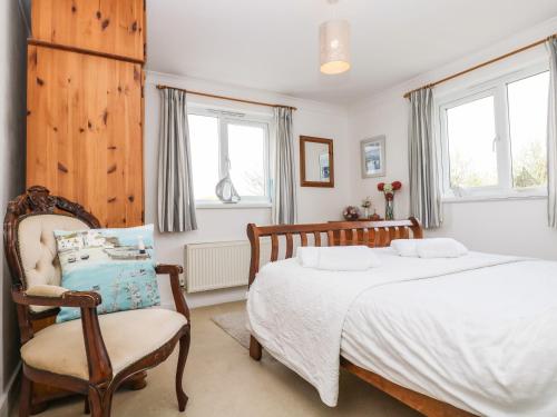 a bedroom with a bed and a chair and windows at Angarrack Farmhouse in Hayle