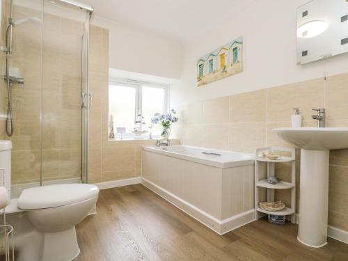 a bathroom with a tub and a toilet and a sink at Angarrack Farmhouse in Hayle