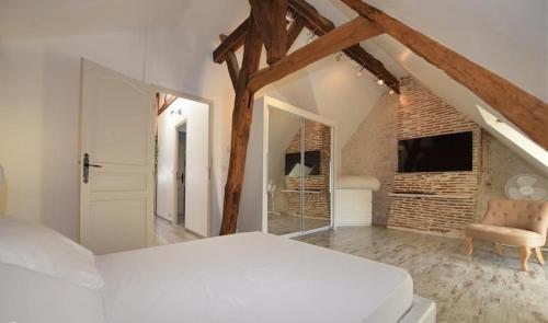 a bedroom with a white bed and a chair in a room at MAISON DE CARACTERE COSY in Sambin