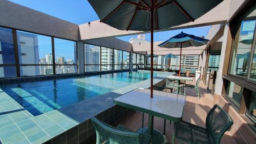 a swimming pool with tables and umbrellas on a building at Flat em Boa Viagem - Edifício Rooftop 470 in Recife