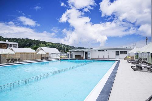 ein großer Pool mit Stühlen und ein Gebäude in der Unterkunft Glamping&Port結 in Shimada