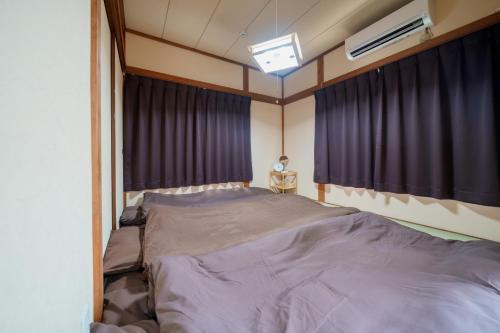 ein Schlafzimmer mit einem großen Bett mit lila Vorhängen in der Unterkunft R-house 4th in Tokio