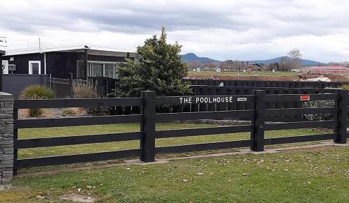 a fence with a sign that reads the pony house at The Poolhouse in Matamata