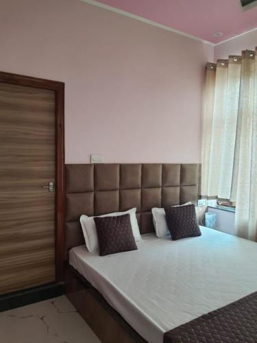 a bedroom with a large bed with a padded headboard at Shree Nanda Guest House in Varanasi