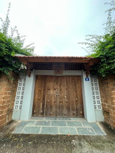 a wooden garage door in a brick building at Asahi Luxstay - Homestay Đường Lâm Hostel in Sơn Tây