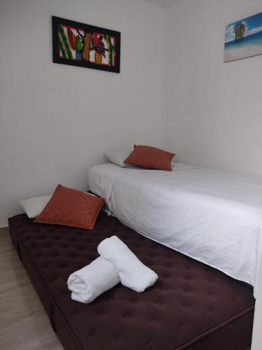 a bedroom with two beds with white towels on a bench at RICAURTE, Moderno, confortable apto, AC, Parquead, Wifi in Ricaurte