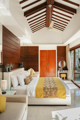 a bedroom with a large bed and a couch at Anari Villas Kuta by The Wina Resorts in Legian