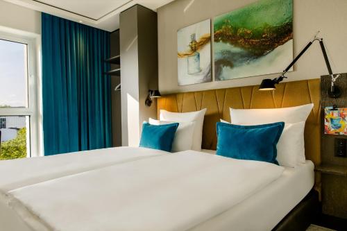 a bedroom with a large white bed with blue pillows at Motel One Köln-Altstadt in Cologne