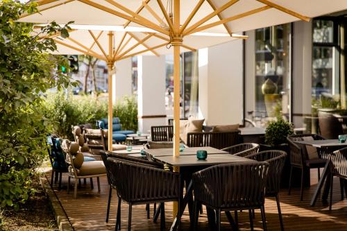 an outdoor restaurant with tables and chairs and umbrellas at Motel One Köln-Altstadt in Cologne