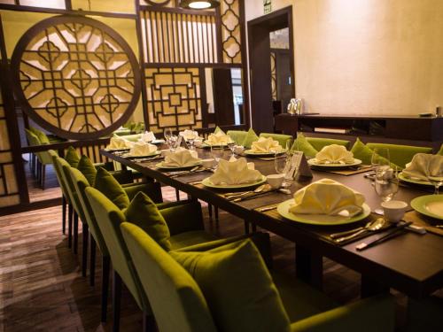 a dining room with long tables and green chairs at Vivanta Colombo, Airport Garden in Negombo