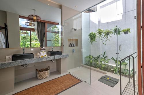 baño con 2 lavabos y ducha de cristal en The Studios Ubud en Ubud