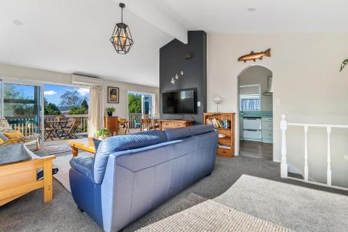 a living room with a blue couch and a television at Rooftops Rotorua in Rotorua