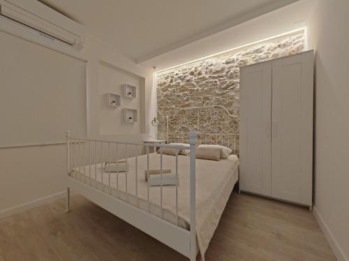 a white bedroom with a bed and a stone wall at Apartments Mateo in Vodice