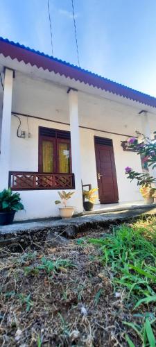 Casa blanca con 2 ventanas y una puerta en Dave Homestay, en Rinondoran