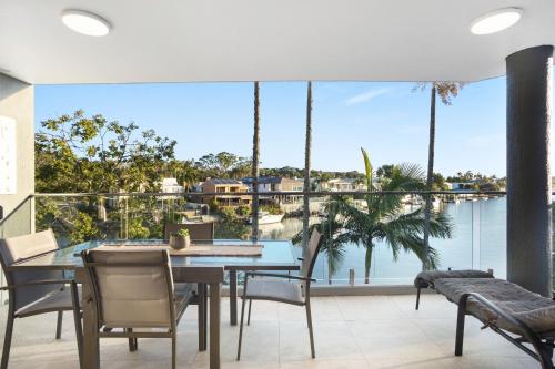 een eetkamer met een tafel en stoelen en een groot raam bij #2 Hastings Street in Noosa Heads