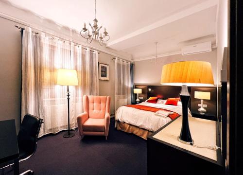 a bedroom with a bed and a chair and a lamp at Excelsior INN in Turda