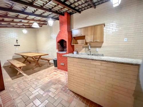 a kitchen with a table and a brick oven at Casa Paris 481 - Sua Mansão na Praia do Morro in Guarapari