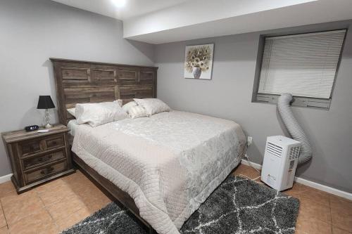 a bedroom with a bed with a wooden headboard and a window at Cozy King Bed, Free Parking! in Newark
