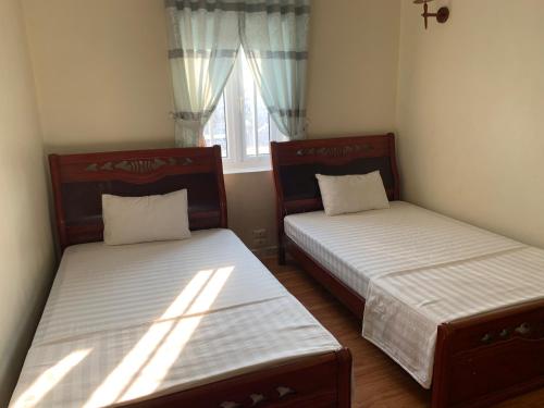 two beds in a small room with a window at Dong Duong Hotel in Hai Phong