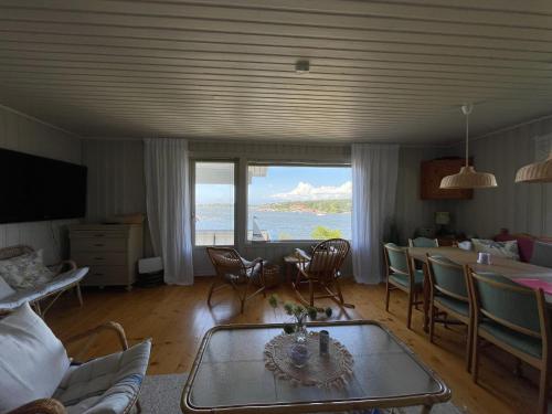 a living room with a table and chairs and a view of the ocean at Fantastisk sjøhytte, 10 sengeplasser, strand og egen brygge in Fredrikstad