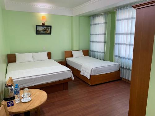 um pequeno quarto com duas camas e uma mesa em Dong Duong Hotel em Haiphong