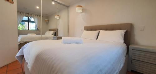 ein Schlafzimmer mit einem großen weißen Bett und einem Spiegel in der Unterkunft Kilifi Beach House in Gnarabup