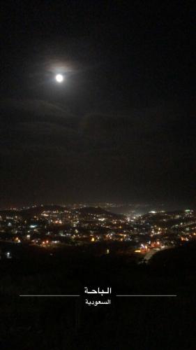 una vista de una ciudad por la noche con una luna en شقة خاصه مطله على الجبل, en Al Bahah