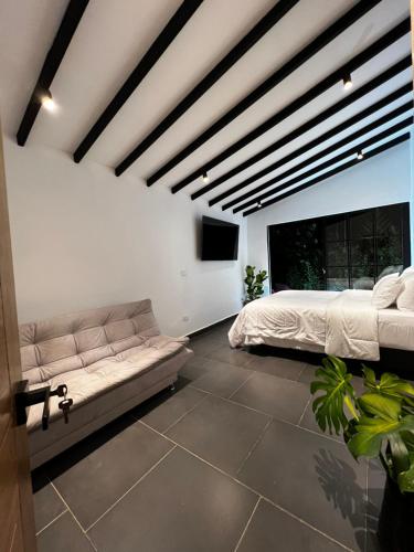 a bedroom with a couch and a tv in it at A 1 minuto del aeropuerto MDE Medellín Rionegro - Casa Campestre Ficus in Rionegro