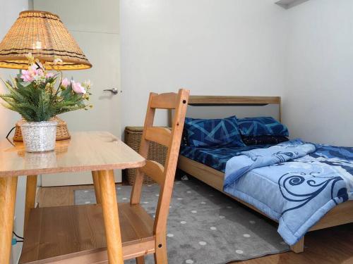 a bedroom with a bed and a table with a lamp at Infina Towers Cozy 2bedroom Condo in Manila