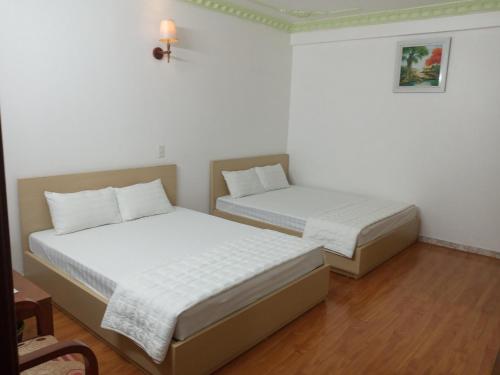 two beds in a room with white walls and wood floors at Dong Duong Hotel in Hai Phong