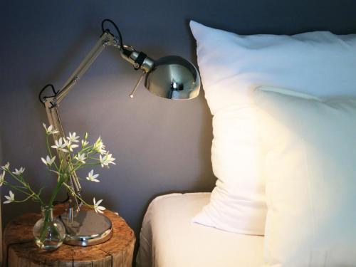 - une lampe sur une table à côté d'un lit avec un oreiller dans l'établissement Małe Letnisko, à Puck