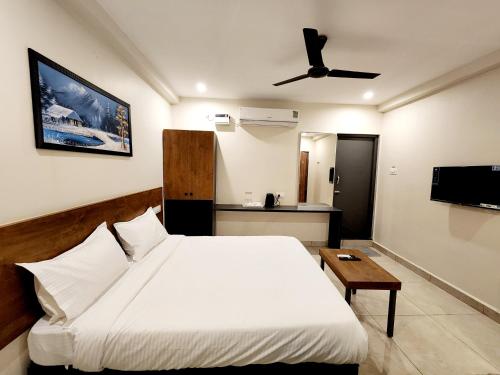 a bedroom with a large white bed and a table at Hotel Park Varaahi in Tirupati