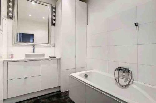 une salle de bain blanche avec une baignoire et un lavabo dans l'établissement Cosy appartement au cœur de Marseille - Paradis, à Marseille