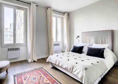une chambre avec un grand lit et deux fenêtres dans l'établissement Cosy appartement au cœur de Marseille - Paradis, à Marseille