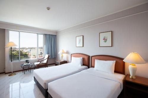 a hotel room with two beds and a window at The Imperial Narathiwat Hotel in Narathiwat