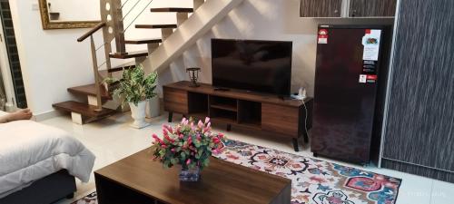 uma sala de estar com televisão e uma mesa com flores em SofiaSuite16, Plaza Azalea, Shah Alam em Shah Alam