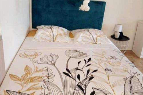 a bed with a blue head board with a floral bedspread at Charmant Studio à Sainte Anne -Plage avec Parking in Sainte-Anne