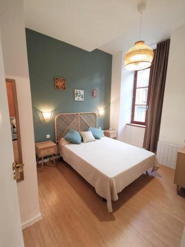 une chambre avec un grand lit blanc avec des oreillers bleus dans l'établissement LA GABICHE - NOUVEAU T2 FACE AUX THERMES, à Aulus-les-Bains