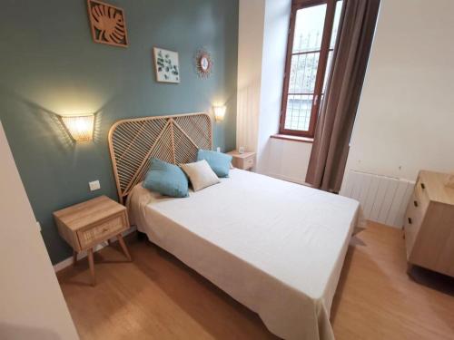 una camera da letto con un grande letto bianco con cuscini blu di LA GABICHE - NOUVEAU T2 FACE AUX THERMES ad Aulus-les-Bains
